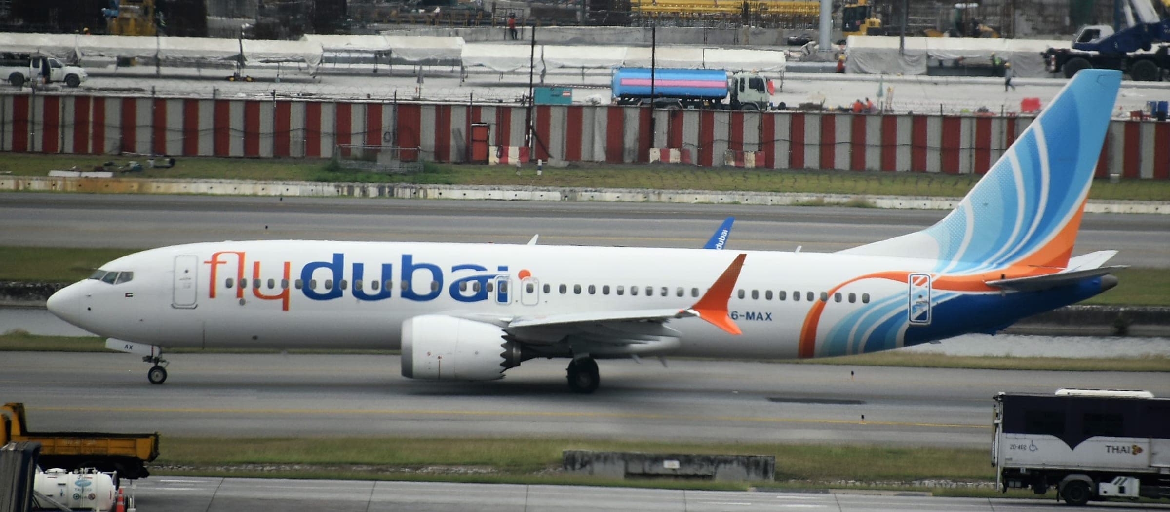 A flydubai Boeing 737 MAX 8, registration A6-MAX, on the ground at Bangkok Suvarnabhumi Airport, in the airline's white livery with a blue and orange tail.
